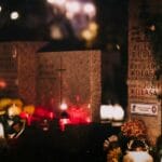 Grave markers covered with lit candles and flower offerings at night, the Filipino Undas tradition of visiting loved ones' graves for All Saints' and All Souls' Day